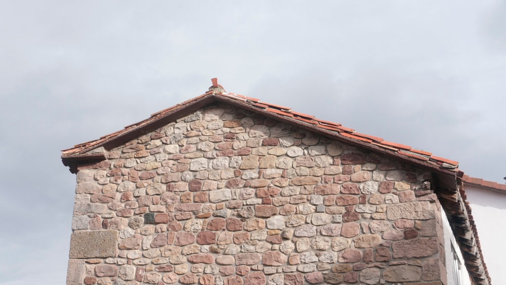 An old stone builting with a double-pitched saltbox roof